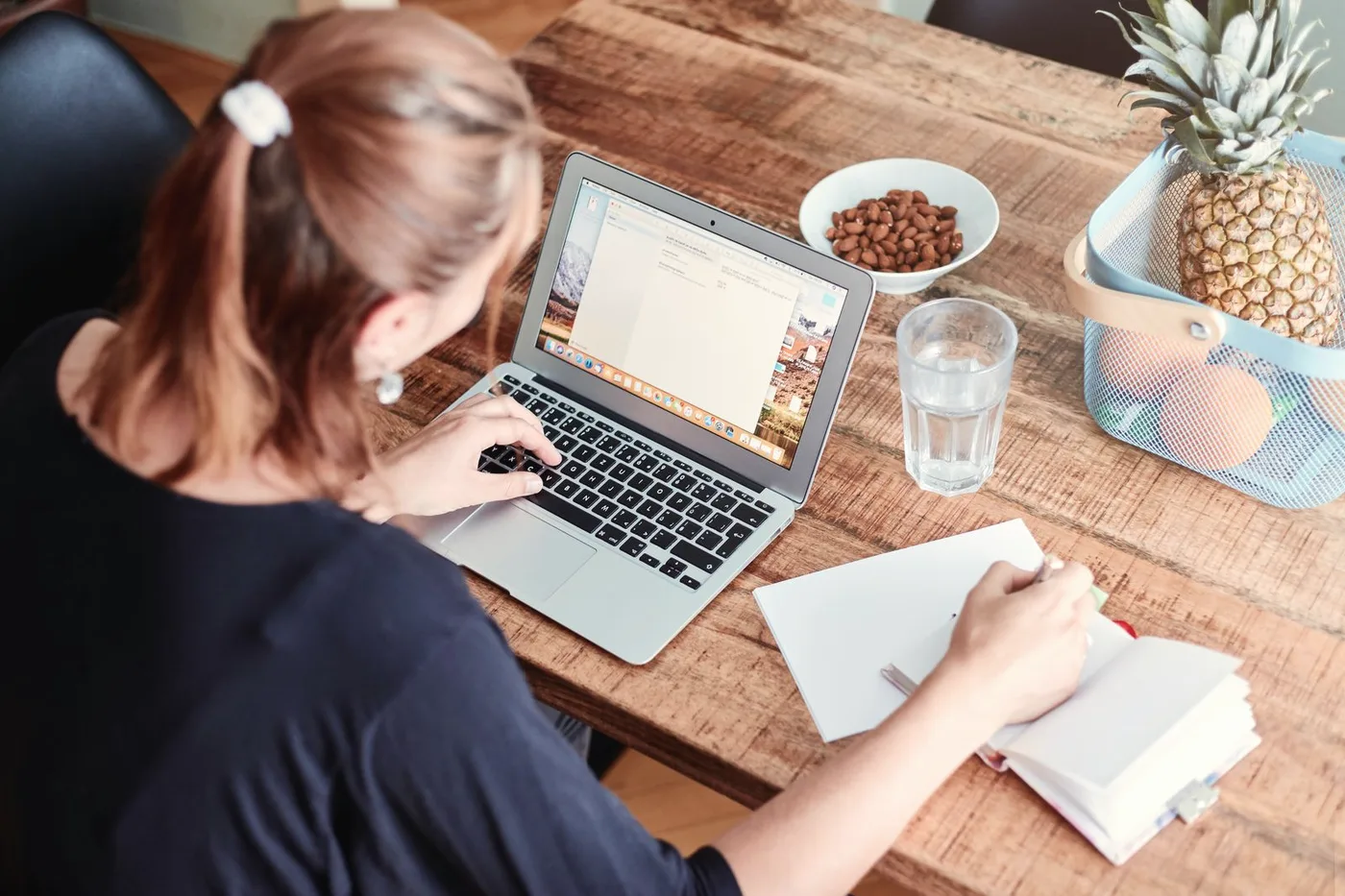 Mulher escrevendo no notebook na mesa de casa