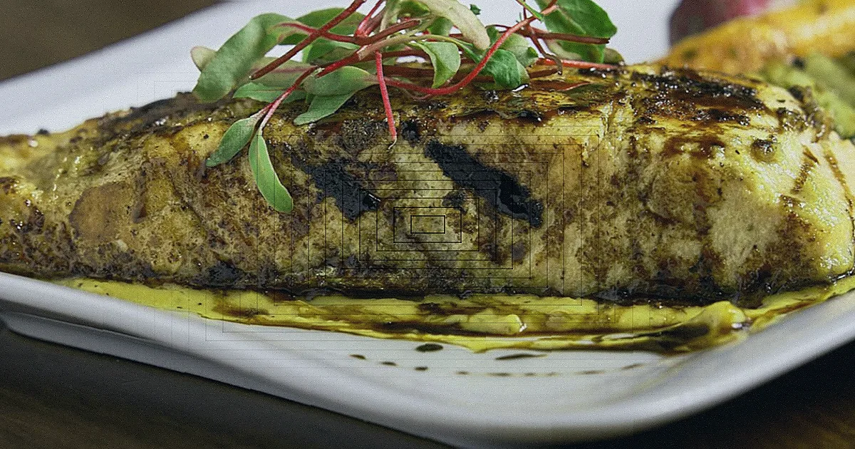 Bife sendo selado em uma frigideira quente com fumaça na cozinha.