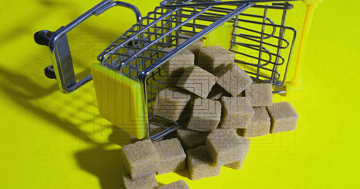 Carrinho de compras cheio de produtos variados em um corredor de supermercado.